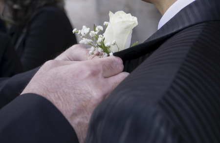 groom wears the boutonniere in a buttonholeの写真素材