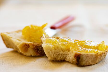 spreading orange jam on a slice of bread