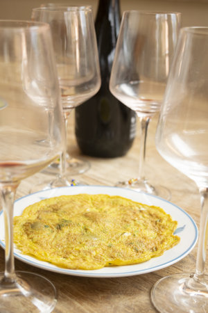 omelette with aromatic herbs and in the background goblets and bottle of wineの写真素材