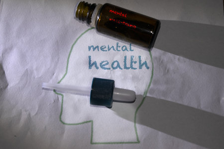 concept of mental health and well-being with a drawing of a brain and a vial of medicineの写真素材