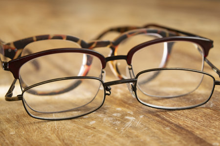 eyeglasses placed in series on a wooden tableの写真素材