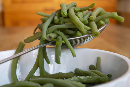 freshly drained cooked green beans on a slotted spoon