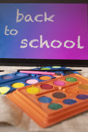 colorful watercolors with the inscription back to school on a tablet
