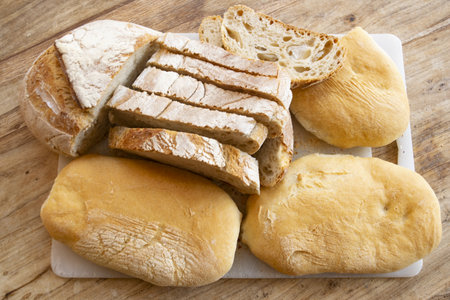 fresh sliced bread and rolls on top of a cutting board