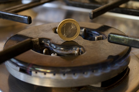 1 euro coin on top of a gas stove as an energy cost conceptの写真素材