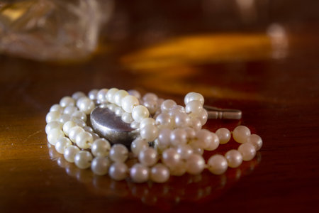 pearl necklace with light reflection on a wooden tableの写真素材