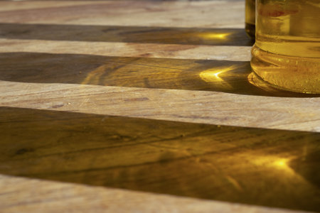 sun reflections of olive oil bottles on a wooden tableの写真素材
