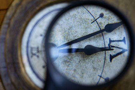 time concept with an old wall clock and a magnifying glass highlighting a detailの写真素材