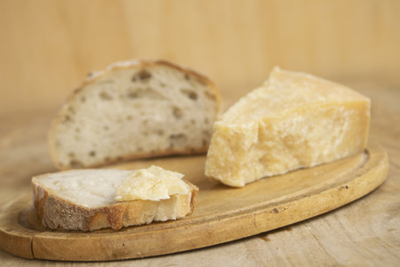 piece of parmesan cheese on a slice of bread on a wooden pastry board