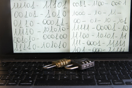 open laptop displaying handwritten binary code on screen with two combination padlocks on the...