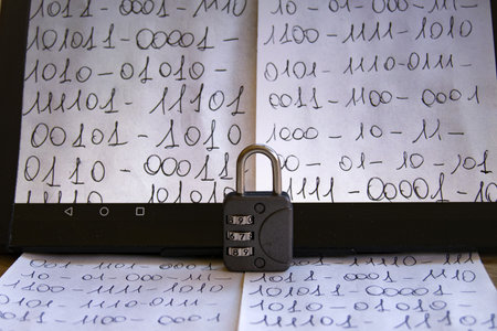 close-up of a tablet screen displaying handwritten binary code, with a combination padlock remaining in front, symbolizing data securityの写真素材