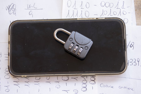 a combination padlock rests on a smartphone screen, symbolizing digital data protectionの写真素材