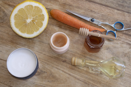 top-down view of a halved lemon, carrot, honey, oil, and two jars of cream, highlighting natural skincareの写真素材