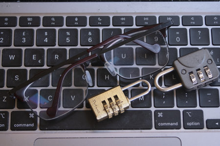 eyeglasses and two combination locks on a laptop keyboard, symbolizing focus on digital security