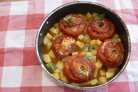 traditional Italian baked tomatoes stuffed with rice and herbs, served with potatoes, rustic home-cooked dishの写真素材