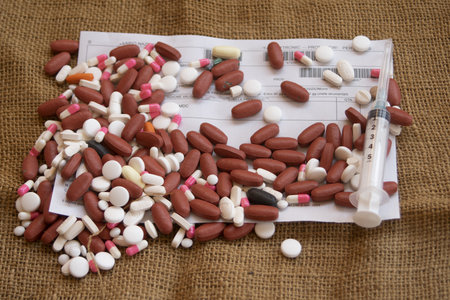 an assortment of pharmaceutical pills and a syringe scattered over a medical prescription form on...