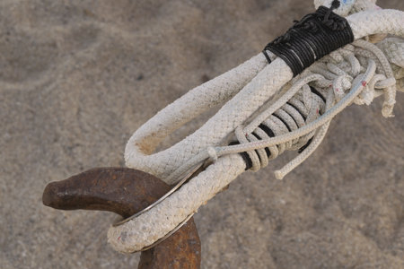 close-up detail of heavy white nautical ropes secured with tight black lashing and complex knotwork on a blurred sandy background. strength, connection, and craftsmanship conceptの写真素材