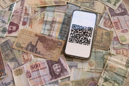 smartphone displaying qr code for digital payment placed on collection of various international...