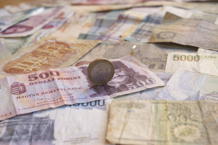 close-up of a one euro coin standing on various old international banknotes, symbolizing global finance, currency exchange, and European economy.の写真素材