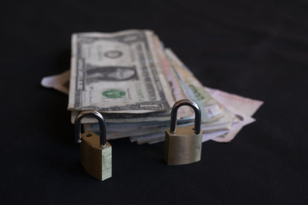 pile of dollar euro and mixed currency banknotes locked with two metal padlocks concept of financial security savings protection money safety investmentの写真素材