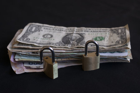 pile of dollar euro and mixed currency banknotes locked with two metal padlocks concept of financial security savings protection money safety investmentの写真素材