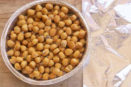 sicilian pignolata fried dough balls covered with honey and colorful sprinkles in aluminum tray traditional italian carnival dessert pastry sweet treatの写真素材