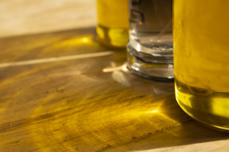 golden olive oil in glass bottle on rustic wooden board, natural cooking ingredient for healthy Mediterranean diet and culinary preparationsの写真素材