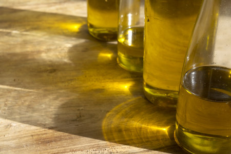 bottles of extra virgin olive oil on rustic wooden table with warm sunlight reflections, Mediterranean healthy food and sustainable agriculture concept.の写真素材
