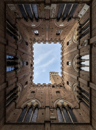 view of the Torre del Mangia and from inside the Courtyard of the Podest? near the public palace of sienaのeditorial素材