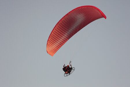 the flight of the paraglider with the motor in the rays of the setting sunの写真素材