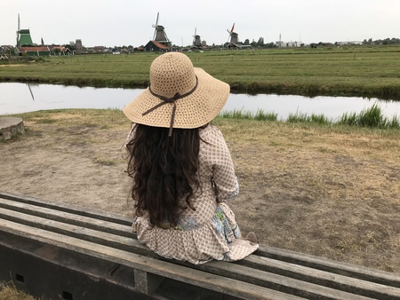 Countryside Woman Wearing a Hat Sitting on a Bench Watching the Beautiful Landscape of a Farmの写真素材