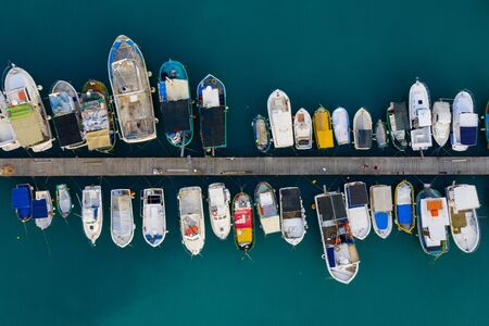 Aerial view of many colorful boats, yachts, fishing vessels on the wood pier. Mediterranean sea