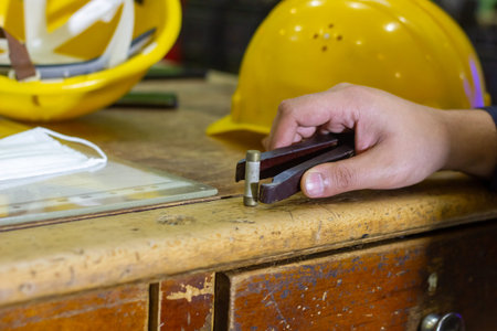 hand of craftsman working on wooden desk with safety helmet and tools