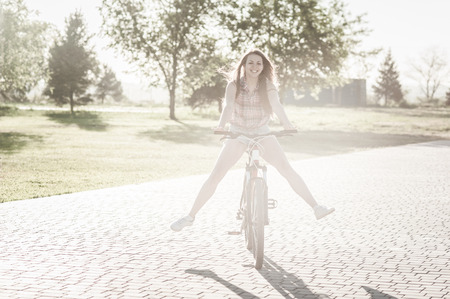 Nice smiling girl riding on bicycle at parkの写真素材