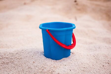 blue empty bucket with red handle, summer, sand.の写真素材