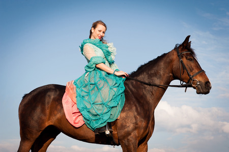 Horsewoman in blue dress on the blue sky backgroundの写真素材