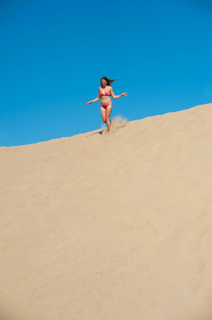Young beautiful girl in red bikini running on sandの写真素材