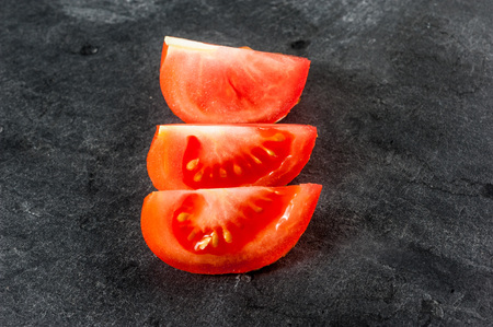 Sliced tomato, three pieces on dark background
の写真素材