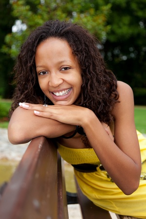 Portrait of a young beautiful african american woman sitting on a benchの写真素材