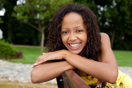 Portrait of a young beautiful african american woman sitting on a benchの写真素材