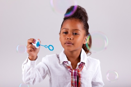Cute little African American girl blowing soap bubblesの写真素材