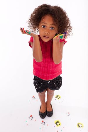 Little African Asian girl with painted hands in colorful paintsの写真素材