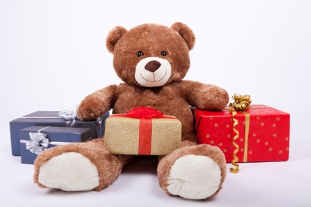 Seated teddy bear with gift boxes, over a white backgroundの写真素材