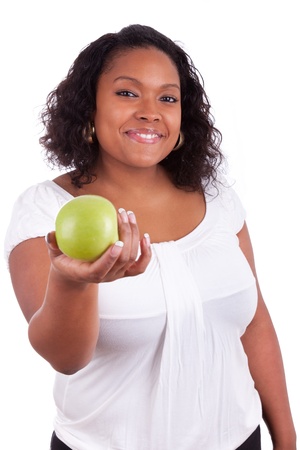 Young african american woman giving an  green apple, isolated on white backgroundの写真素材