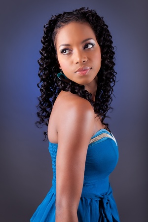 Portrait of a young beautiful african american woman in blue dress looking upの写真素材