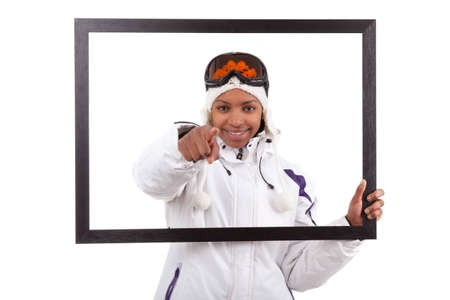 Young smiley woman in ski gears  holding a picture frame, isolated on white backgroundの写真素材