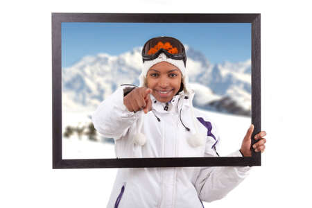 Young smiley woman in ski gears  holding a picture frame, isolated on white backgroundの写真素材