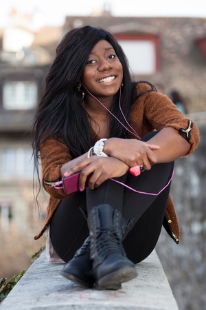 Outdoor of a  portrait happy young african american teenage girl listening to musicの写真素材