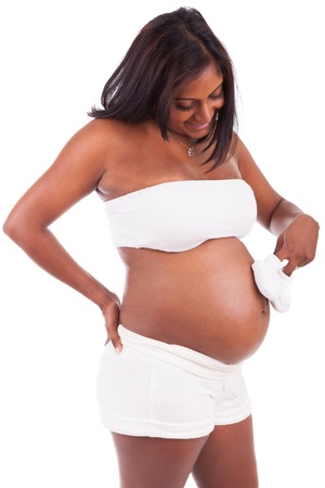 Young pregnant indian woman holding baby shoes, isolated on white backgroundの写真素材