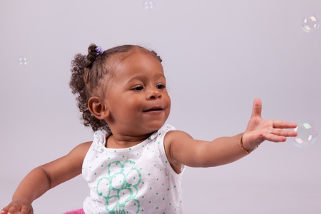 Cute little African American girl playing with soap bubblesの写真素材